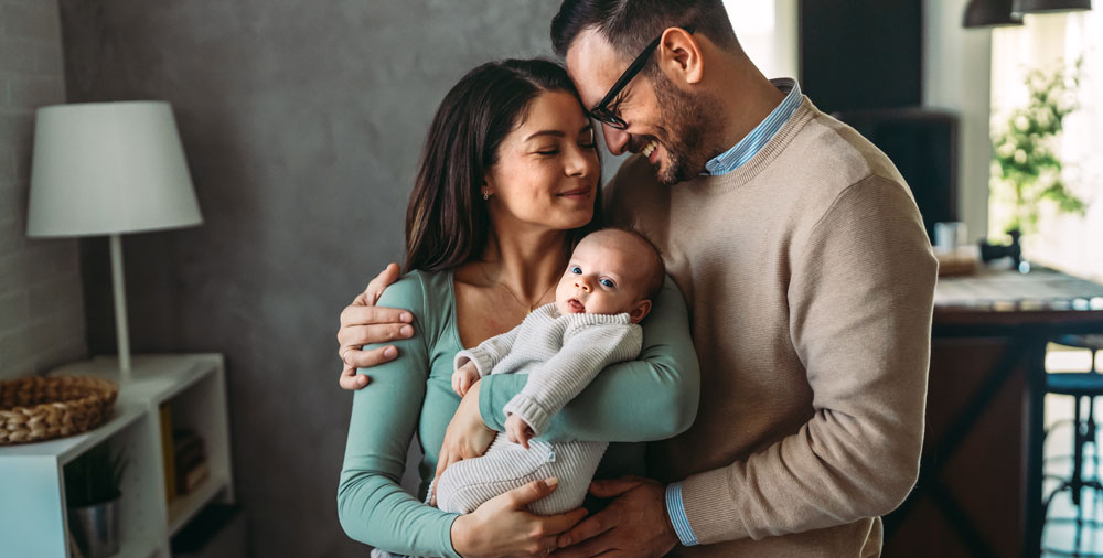 Parents-spend-happy-moments-with-the-newborn-child-2 Parents smiling and holding a new baby